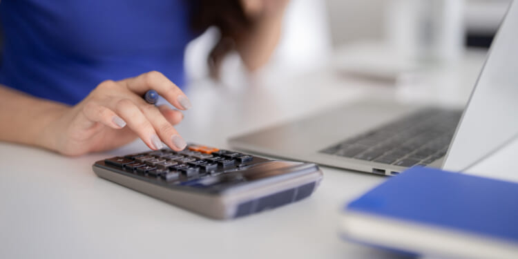Someone doing their taxes, at a laptop with a calculator. Stress is due to Kansas' high taxes at multiple levels, and the state should focus on tax competitiveness.