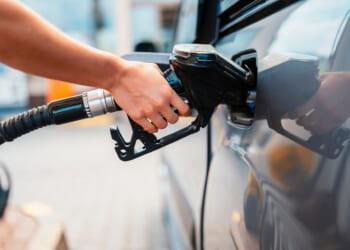 Closeup of woman pumping gasoline fuel in car at gas station. Dealing with high fuel prices.
