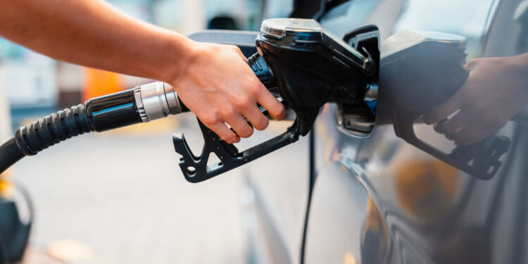 Closeup of woman pumping gasoline fuel in car at gas station. Dealing with high fuel prices.