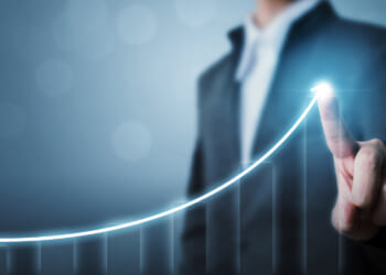 An image of a man drawing the outline of a graph increasing and going up, demonstrating the economic growth of small business.