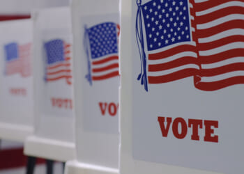Voting booths lined up, with the word "vote" and the American flag on them, in preparation for an election.