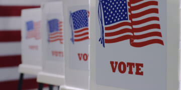 Voting booths lined up, with the word "vote" and the American flag on them, in preparation for an election.