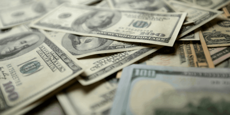 Close-up of a scattered pile of U.S. dollar bills, primarily $100 denominations, symbolizing government spending and fiscal policy in Kansas. The image highlights the concept of dedicated funds and their impact on accountability and transparency in public finance, as discussed in the Kansas Policy Institute article on undermining accountability in government budgets.